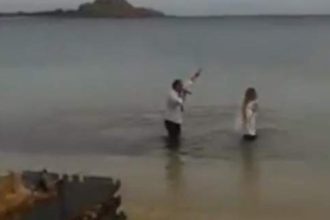 Τραγουδιστής με το μικρόφωνο στο χέρι βουτά στα παγωμένα νερά της Μυκόνου μαζί με τουρίστρια - ΒΙΝΤΕΟ